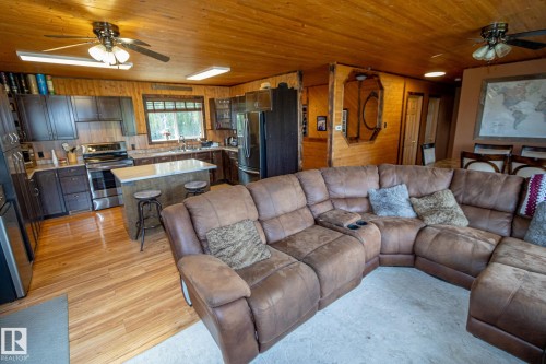 Living room with ceiling fan, wood walls, light wood-type flooring, and wood ceiling - 56430 Range Rd 113, Rural St. Paul County, AB - Indoor Photo Showing Living Room