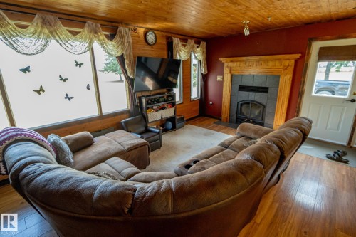 Living area featuring wood ceiling, hardwood / wood-style floors, and a tiled fireplace - 56430 Range Rd 113, Rural St. Paul County, AB - Indoor Photo Showing Living Room With Fireplace