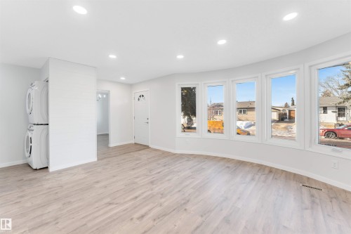 Unfurnished living room featuring recessed lighting, light wood finished floors, and stacked washer and dryer - 14511 21 St., Edmonton, AB - Indoor Photo Showing Other Room