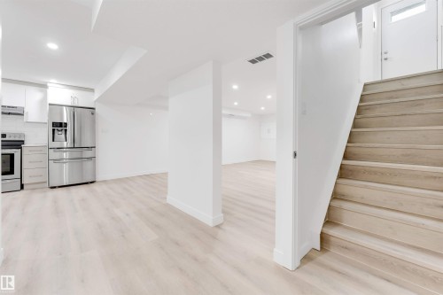 Kitchen with stainless steel appliances, white cabinets, decorative backsplash, recessed lighting, and exhaust hood - 14511 21 St., Edmonton, AB - Indoor
