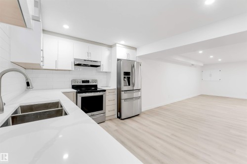 Kitchen featuring stainless steel appliances, white cabinetry, recessed lighting, light wood-style floors, and light stone countertops - 14511 21 St., Edmonton, AB - Indoor Photo Showing Kitchen With Double Sink With Upgraded Kitchen