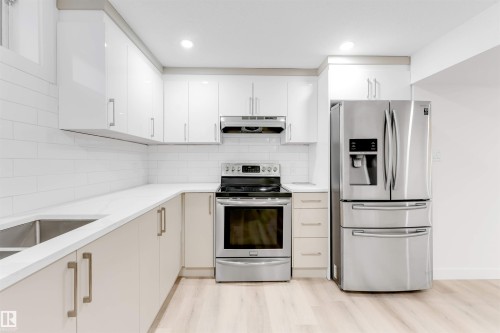 Kitchen with stainless steel appliances, light wood-type flooring, light stone countertops, recessed lighting, and decorative backsplash - 14511 21 St., Edmonton, AB - Indoor Photo Showing Kitchen With Upgraded Kitchen