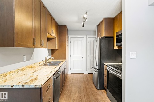 Kitchen featuring wood finish cabinets, light wood-style floors, stainless steel appliances, a textured ceiling, and track lighting - 914 9 Street, Cold Lake, AB - Indoor Photo Showing Kitchen With Double Sink
