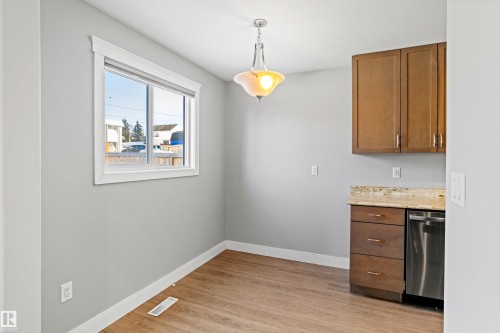 Dining area with hanging light fixtures, light wood-type flooring, dishwasher, light countertops, and wood finish cabinetry - 914 9 Street, Cold Lake, AB - Indoor