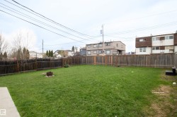 Expansive fenced backyard featuring a substantial lawn area and a designated fire pit - 
