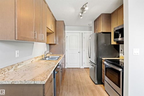 Kitchen featuring stainless steel appliances, light wood-type flooring, light stone counters, and wood finish cabinets - 914 9 Street, Cold Lake, AB - Indoor Photo Showing Kitchen With Double Sink