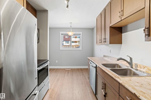 Kitchen with stainless steel appliances, light wood-style floors, a textured ceiling, wood finish cabinetry, and rail lighting - 914 9 Street, Cold Lake, AB - Indoor Photo Showing Kitchen With Double Sink