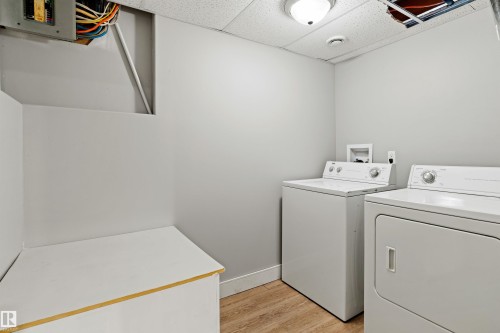 Laundry room featuring light wood-type flooring, a paneled ceiling, and washing machine and clothes dryer - 914 9 Street, Cold Lake, AB - Indoor Photo Showing Laundry Room