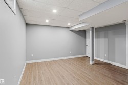 Finished basement featuring a paneled ceiling, light wood-type flooring, and recessed lighting - 