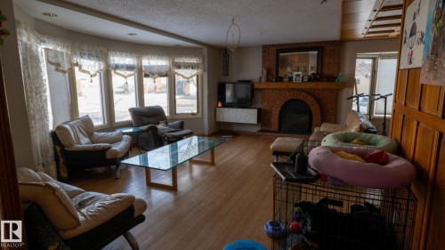 Living area featuring hardwood / wood-style floors, a textured ceiling, and a fireplace - 11 Austin Crescent, St. Albert, AB - Indoor Photo Showing Living Room With Fireplace
