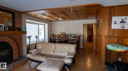 Living area featuring a fireplace, wood finished floors, wooden walls, and a textured ceiling - 11 Austin Crescent, St. Albert, AB - Indoor Photo Showing Living Room With Fireplace