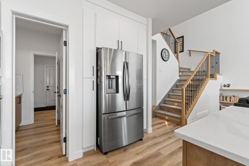 Kitchen with stainless steel refrigerator with ice dispenser, light wood-style flooring, and white cabinets - 342 Meadowview Drive, Fort Saskatchewan, AB - Indoor