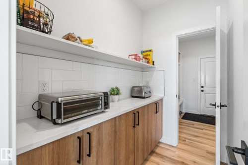 Kitchen featuring open shelves, wood finish cabinets, light wood-type flooring, decorative backsplash, and light stone counters - 342 Meadowview Drive, Fort Saskatchewan, AB - Indoor