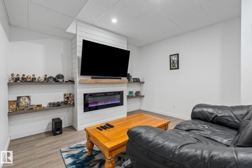 Living room with light wood-type flooring, a glass covered fireplace, and a paneled ceiling - 342 Meadowview Drive, Fort Saskatchewan, AB - Indoor Photo Showing Living Room With Fireplace
