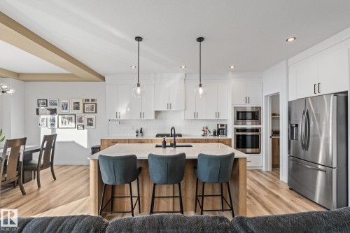 Kitchen featuring stainless steel appliances, light wood-type flooring, decorative light fixtures, two tone cabinetry, and a kitchen bar - 342 Meadowview Drive, Fort Saskatchewan, AB - Indoor Photo Showing Kitchen With Upgraded Kitchen