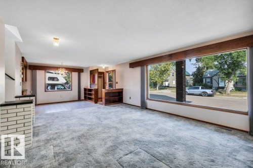 Unfurnished living room with a chandelier and carpet - 4314 52 Street, Wetaskiwin, AB - Indoor