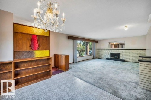 Unfurnished living room featuring carpet flooring, suspended lighting, and a fireplace - 4314 52 Street, Wetaskiwin, AB - Indoor With Fireplace