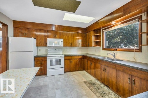 Kitchen with white appliances, backsplash, wood finish cabinets, and open shelves - 4314 52 Street, Wetaskiwin, AB - Indoor Photo Showing Kitchen With Double Sink