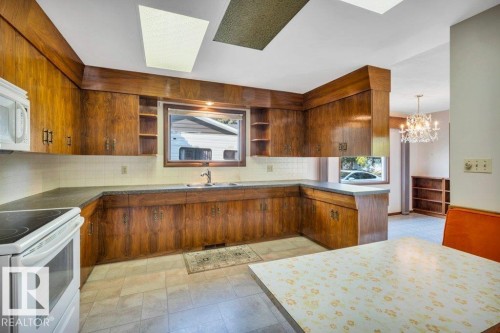 Kitchen with white appliances, open shelves, a peninsula, decorative backsplash, and wood finish cabinetry - 4314 52 Street, Wetaskiwin, AB - Indoor Photo Showing Kitchen With Double Sink