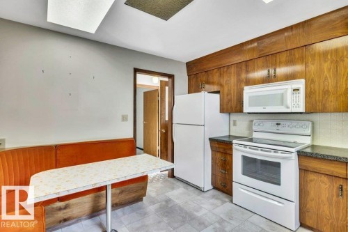 Kitchen with white appliances, wood finish cabinets, and dark countertops - 4314 52 Street, Wetaskiwin, AB - Indoor Photo Showing Kitchen