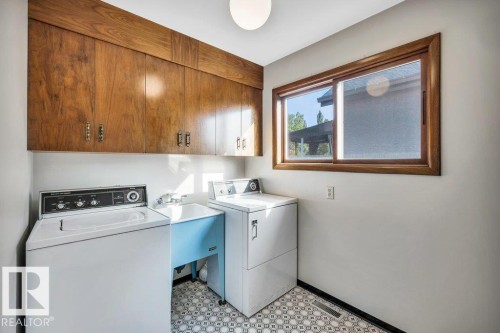 Laundry room with light floors, cabinet space, and washing machine and clothes dryer - 4314 52 Street, Wetaskiwin, AB - Indoor Photo Showing Laundry Room