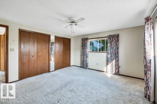 Unfurnished bedroom featuring two closets, a textured ceiling, carpet flooring, and ceiling fan - 4314 52 Street, Wetaskiwin, AB - Indoor Photo Showing Other Room