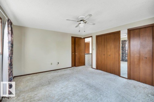 Unfurnished bedroom featuring a textured ceiling, carpet floors, two closets, and ceiling fan - 4314 52 Street, Wetaskiwin, AB - Indoor Photo Showing Other Room