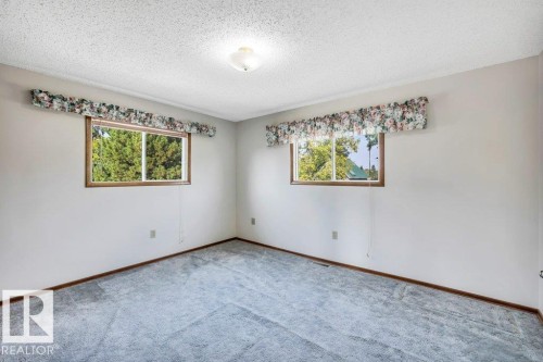 Carpeted spare room featuring a textured ceiling and baseboards - 4314 52 Street, Wetaskiwin, AB - Indoor Photo Showing Other Room