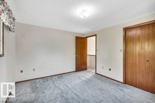Unfurnished bedroom with a textured ceiling, carpet flooring, and a closet - 4314 52 Street, Wetaskiwin, AB - Indoor Photo Showing Other Room