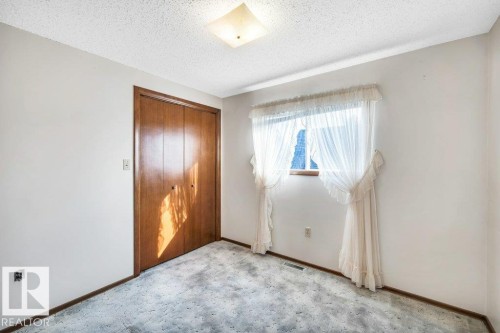 Unfurnished bedroom with a textured ceiling, a closet, and carpet floors - 4314 52 Street, Wetaskiwin, AB - Indoor Photo Showing Other Room