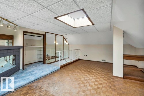 Additional living space featuring a tiled fireplace, parquet floors, vaulted ceiling, and a skylight - 4314 52 Street, Wetaskiwin, AB - Indoor Photo Showing Other Room