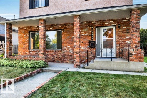 Doorway to property with a porch, brick siding, stucco siding, and a lawn - 4314 52 Street, Wetaskiwin, AB - Outdoor With Deck Patio Veranda