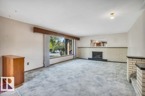 Unfurnished living room with a brick fireplace and carpet - 4314 52 Street, Wetaskiwin, AB - Indoor With Fireplace