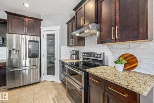 Kitchen featuring dark wood finish cabinetry, stainless steel appliances, light stone counters, and recessed lighting - 167 Bremner Crescent, Fort Saskatchewan, AB - Indoor Photo Showing Kitchen With Stainless Steel Kitchen With Upgraded Kitchen