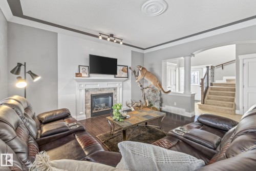 Living area with wood finished floors, arched walkways, decorative columns, and a glass covered fireplace - 167 Bremner Crescent, Fort Saskatchewan, AB - Indoor Photo Showing Living Room With Fireplace