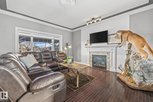 Living area featuring a tile fireplace, wood-type flooring, and track lighting - 167 Bremner Crescent, Fort Saskatchewan, AB - Indoor Photo Showing Living Room With Fireplace