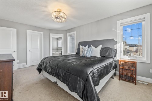 Bedroom with connected bathroom, light carpet, and suspended lighting - 167 Bremner Crescent, Fort Saskatchewan, AB - Indoor Photo Showing Bedroom