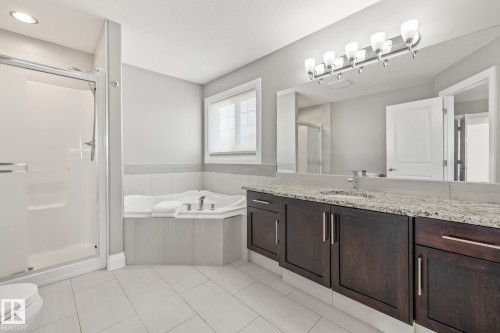 Full bathroom with vanity, a stall shower, a bath, light tile patterned floors, and wainscoting - 167 Bremner Crescent, Fort Saskatchewan, AB - Indoor Photo Showing Bathroom