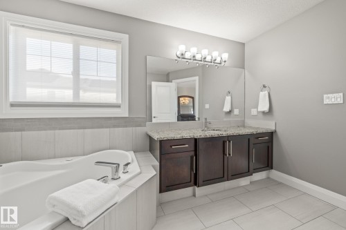 Bathroom with vanity, a bath, light tile patterned flooring, and a textured ceiling - 167 Bremner Crescent, Fort Saskatchewan, AB - Indoor Photo Showing Bathroom