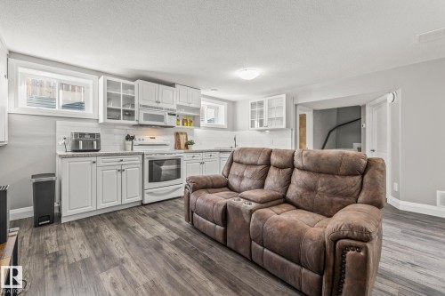 Kitchen with tasteful backsplash, white cabinets, white appliances, glass insert cabinets, and dark wood-style flooring - 167 Bremner Crescent, Fort Saskatchewan, AB - Indoor
