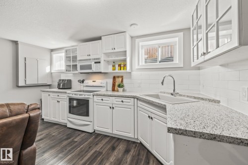 Kitchen featuring glass fronted cabinets, white appliances, white cabinets, dark wood-type flooring, and a textured ceiling - 167 Bremner Crescent, Fort Saskatchewan, AB - Indoor Photo Showing Kitchen