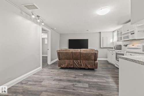 Kitchen with white cabinets, light countertops, white appliances, dark wood-type flooring, and a textured ceiling - 167 Bremner Crescent, Fort Saskatchewan, AB - Indoor