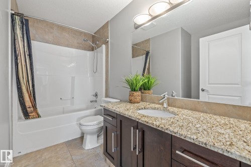 Full bathroom with vanity, a textured ceiling, shower / bath combination with curtain, and light tile patterned floors - 167 Bremner Crescent, Fort Saskatchewan, AB - Indoor Photo Showing Bathroom
