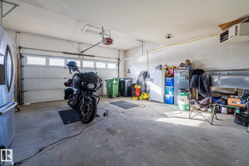 Garage with a heating unit, stainless steel refrigerator with ice dispenser, and a garage door opener - 167 Bremner Crescent, Fort Saskatchewan, AB - Indoor Photo Showing Garage