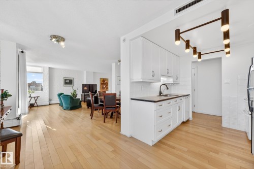 Kitchen featuring white cabinetry, light wood finished floors, dark countertops, open floor plan, and decorative backsplash - 1502 10160 115 Street, Edmonton, AB - Indoor