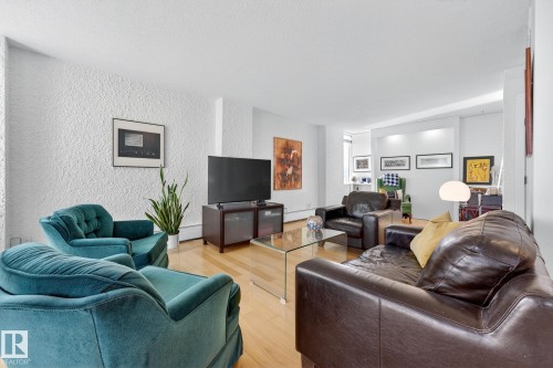 Living area with a textured wall, wood finished floors, and a baseboard radiator - 1502 10160 115 Street, Edmonton, AB - Indoor Photo Showing Living Room