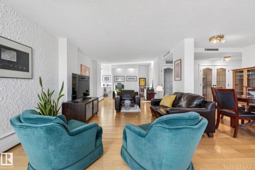 Living area with a textured wall and light wood finished floors - 1502 10160 115 Street, Edmonton, AB - Indoor Photo Showing Living Room