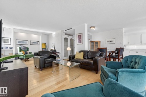 Living area with light wood-type flooring, a textured wall, and french doors - 1502 10160 115 Street, Edmonton, AB - Indoor Photo Showing Living Room