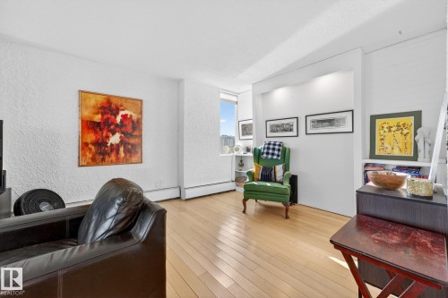 Living area with hardwood / wood-style flooring, a textured wall, and a baseboard radiator - 1502 10160 115 Street, Edmonton, AB - Indoor