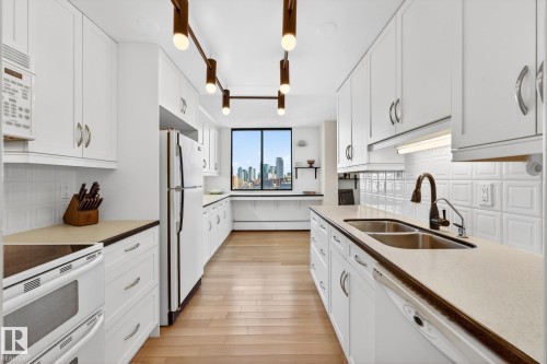 Kitchen featuring white appliances, tasteful backsplash, and white cabinetry - 1502 10160 115 Street, Edmonton, AB - Indoor Photo Showing Kitchen With Double Sink